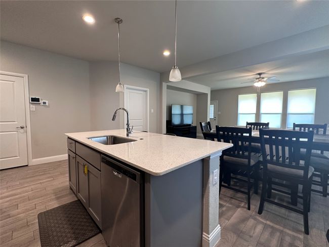 Kitchen featuring stainless steel dishwasher, wood finished floors, a kitchen island with sink, recessed lighting, and a ceiling fan | Image 8