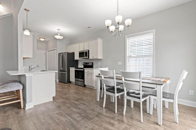 Dining area with baseboards, wood finished floors, and a notable chandelier | Image 18