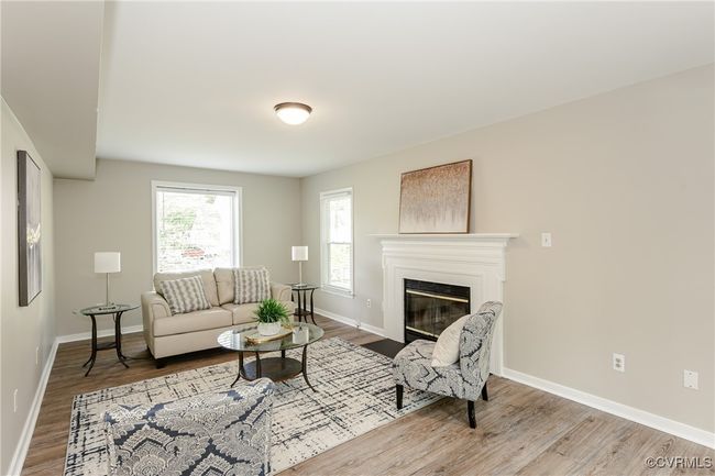 Living room with a fireplace with flush hearth, baseboards, and wood finished floors | Image 24