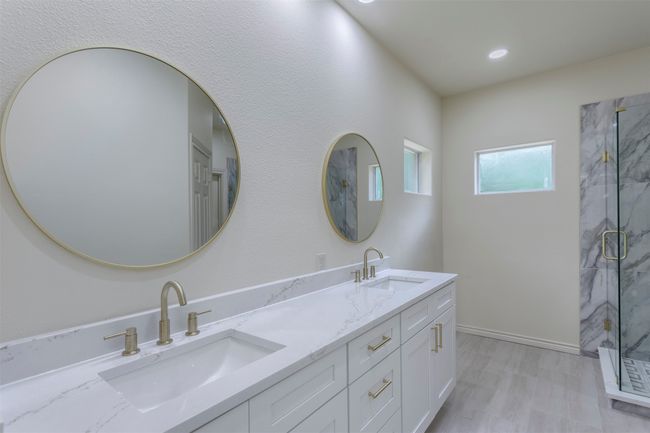 Bathroom featuring a marble finish shower, double vanity, wood finished floors, recessed lighting, and baseboards | Image 20