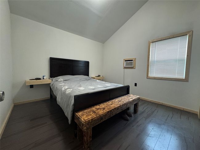 Bedroom featuring vaulted ceiling, dark wood-style floors, and a wall unit AC | Image 8