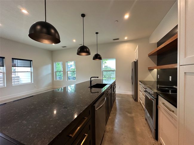 Kitchen with appliances with stainless steel finishes, open shelves, a large island with sink, recessed lighting, and healthy amount of natural light | Image 24