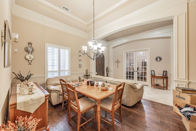 Dining space featuring arched walkways, a chandelier, french doors, dark wood-style floors, and crown molding | Image 11