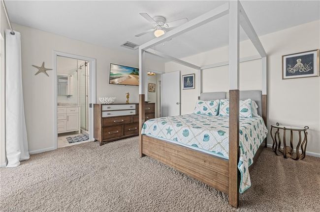 Bedroom with visible vents, baseboards, light carpet, and ensuite bathroom | Image 11
