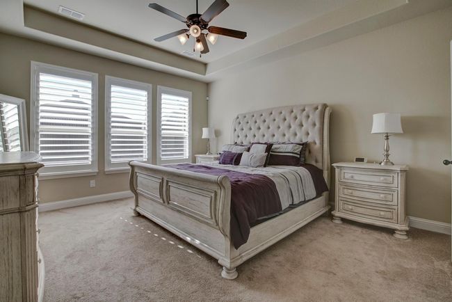 Bedroom featuring light carpet, a tray ceiling, and a ceiling fan | Image 14