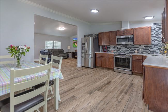 Kitchen with backsplash, crown molding, appliances with stainless steel finishes, light countertops, and light wood finished floors | Image 6