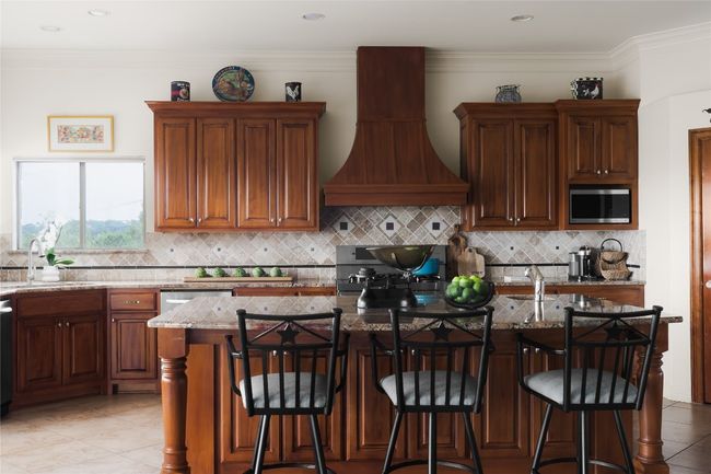 Kitchen featuring a sink, stainless steel microwave, premium range hood, light stone countertops, and backsplash | Image 20