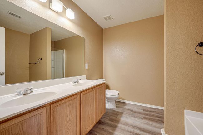 Full bathroom featuring a textured wall, wood finished floors, double vanity, and a shower | Image 17