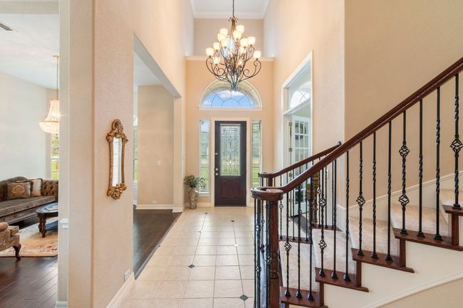 Foyer featuring a high ceiling, stairway, a chandelier, ornamental molding, and baseboards | Image 10