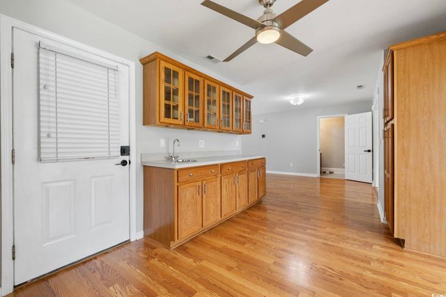 Kitchen with brown cabinets, a sink, light countertops, and light wood finished floors | Image 32