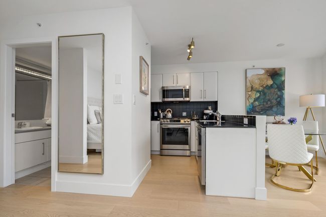 Kitchen featuring white cabinetry, dark countertops, appliances with stainless steel finishes, and a sink | Image 11