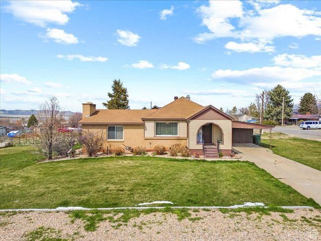 View of front of home with driveway, a front yard, brick siding, an attached carport, and a chimney | Image 4
