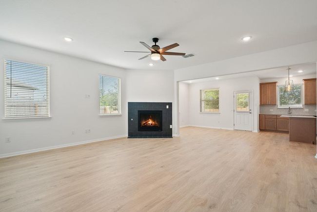 Unfurnished living room featuring ceiling fan, recessed lighting, light wood-type flooring, and a fireplace | Image 7