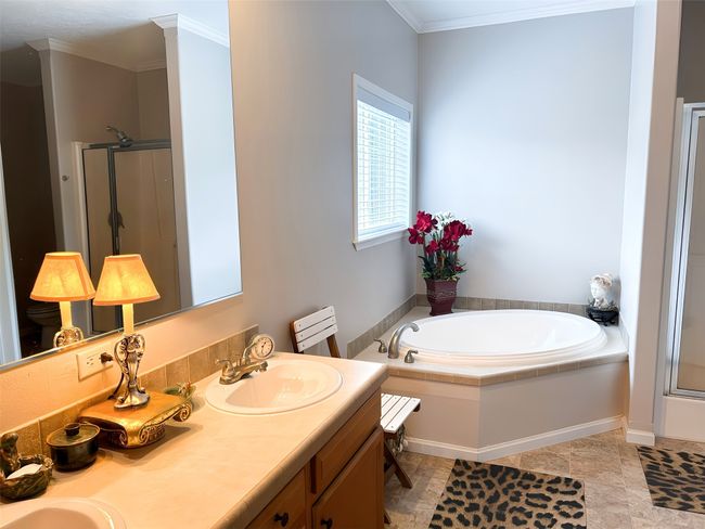 Bathroom featuring a bath, crown molding, double vanity, a sink, and a stall shower | Image 7