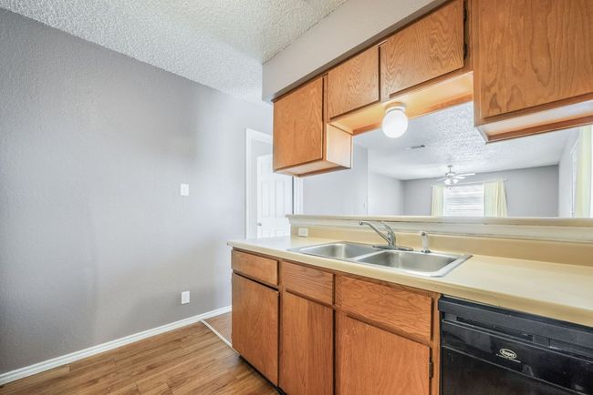 Kitchen featuring dishwasher, light countertops, a textured ceiling, light wood-style floors, and ceiling fan | Image 16