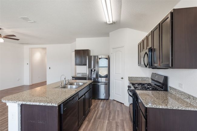 Kitchen featuring black appliances, dark brown cabinets, wood finished floors, a ceiling fan, and lofted ceiling | Image 8