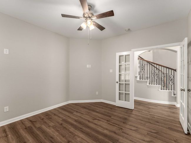 Unfurnished room with stairway, baseboards, dark wood finished floors, ceiling fan, and french doors | Image 5