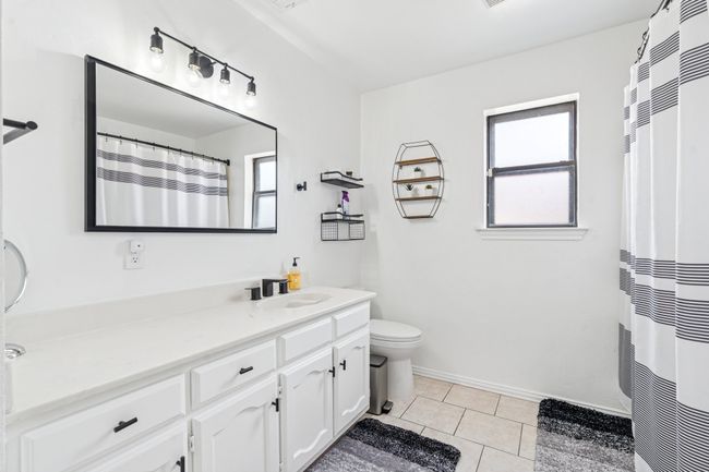 Hall bath with extended countertop, tiled shower, and updated black framed mirror, lighting, and faucet! | Image 20