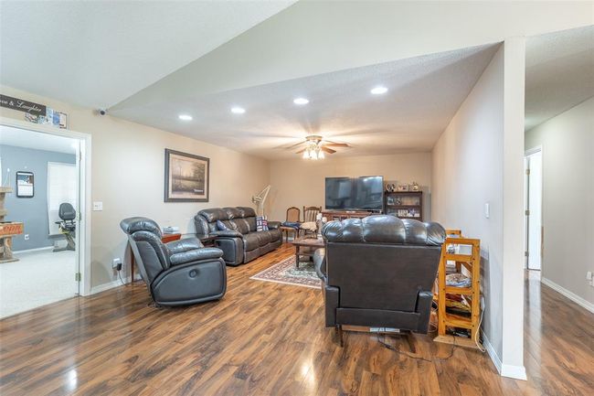 Living room featuring wood finished floors, ceiling fan, recessed lighting, baseboards, and lofted ceiling | Image 15