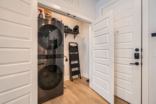 Laundry room with stacked washer / dryer and light wood finished floors | Image 5