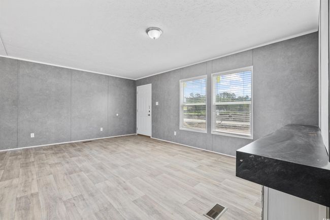 Unfurnished living room with light wood-type flooring, crown molding, and a textured ceiling | Image 9