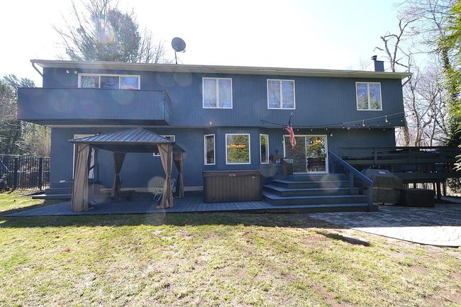Rear view of house with a hot tub, a wooden deck, a lawn, and a gazebo | Image 23