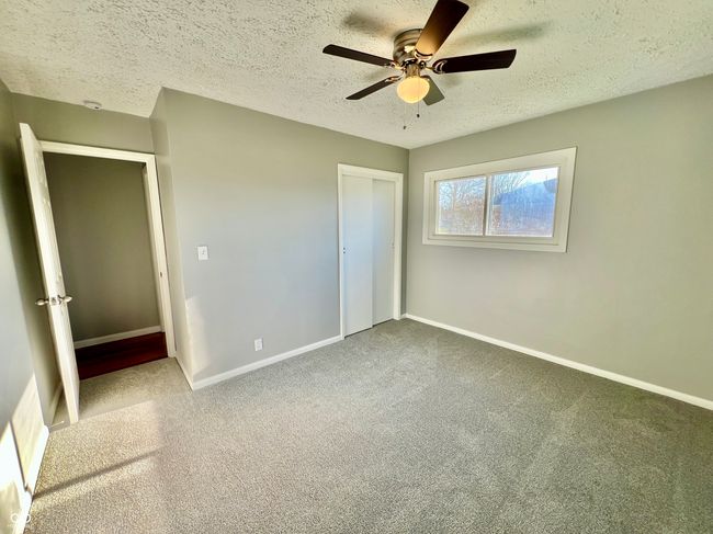 unfurnished bedroom featuring a closet, baseboards, a textured ceiling, carpet floors, and ceiling fan | Image 18
