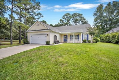 Ranch-style home with a front lawn, a garage, and a porch | Image 1