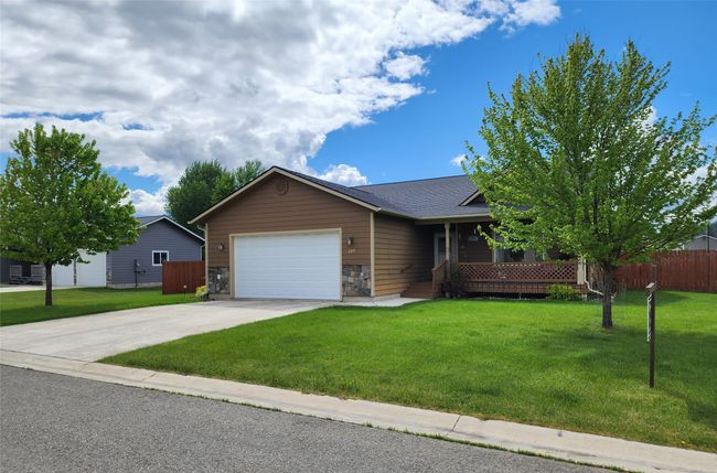 Ranch-style home featuring a garage, concrete driveway, covered porch, and a shingled roof | Image 50