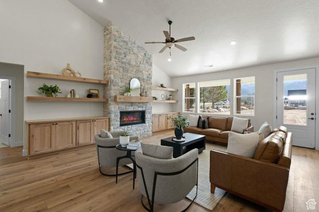 Living room with high vaulted ceiling, a ceiling fan, light wood-style flooring, a fireplace, and recessed lighting | Image 5