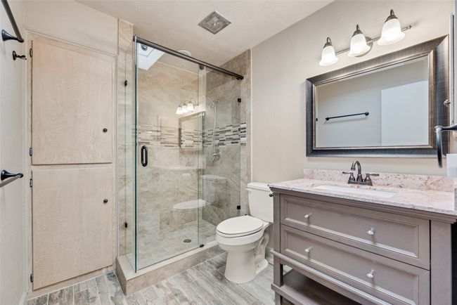 Bathroom featuring wood finished floors, toilet, vanity, and a stall shower | Image 22