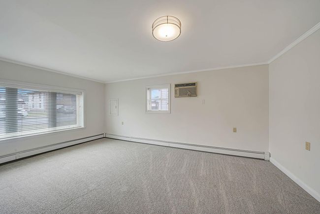 Carpeted empty room featuring ornamental molding, a healthy amount of sunlight, and a wall mounted air conditioner | Image 29