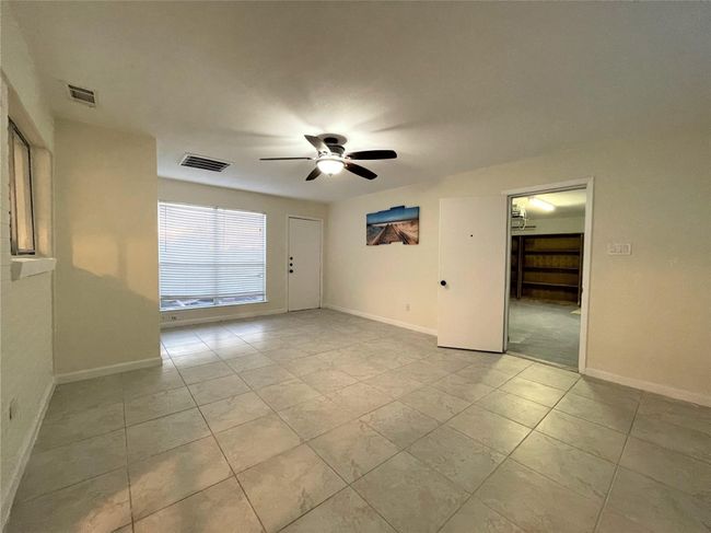 Empty room with ceiling fan and light tile patterned floors | Image 15