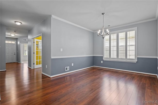 Empty room with a chandelier, wood finished floors, and ornamental molding | Image 11
