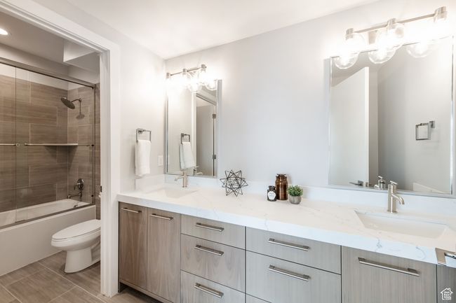 Full bathroom featuring combined bath / shower with glass door, toilet, and vanity | Image 16