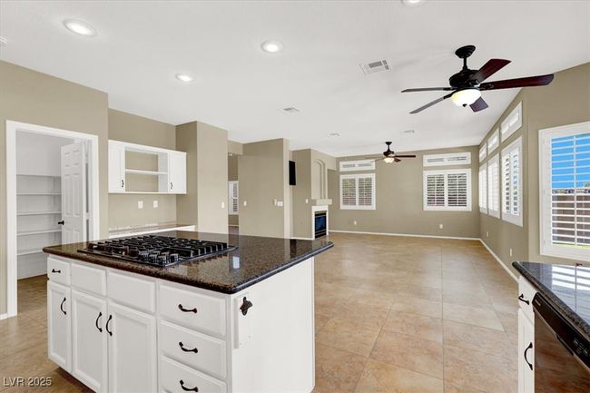 Kitchen featuring a ceiling fan, dishwashing machine, open shelves, stainless steel gas stovetop, and a center island | Image 15