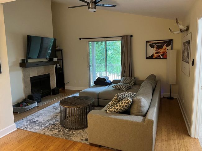 Living room with ceiling fan, wood finished floors, lofted ceiling, and a tiled fireplace | Image 12