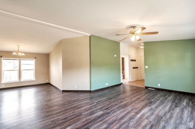 Spare room featuring wood finished floors, a chandelier, a ceiling fan, and baseboards | Image 9