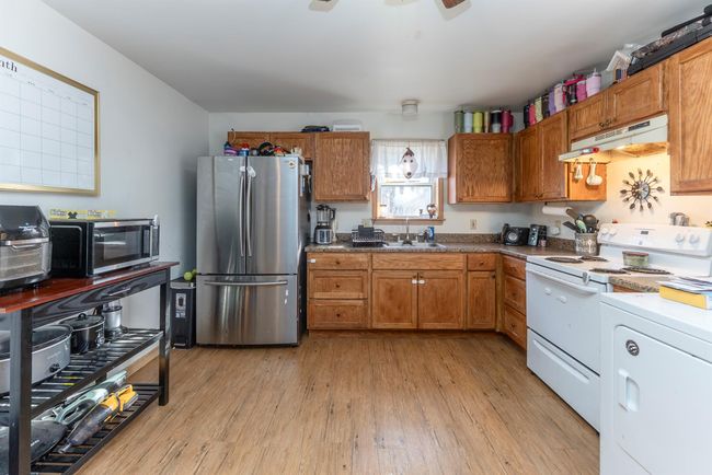 Kitchen featuring light wood-style flooring, under cabinet range hood, brown cabinetry, stainless steel appliances, and a sink | Image 28