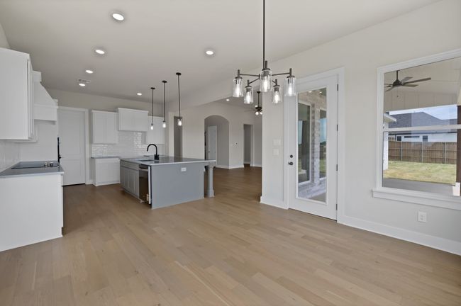 Kitchen featuring open floor plan, arched walkways, backsplash, white cabinetry, and light wood-type flooring | Image 13