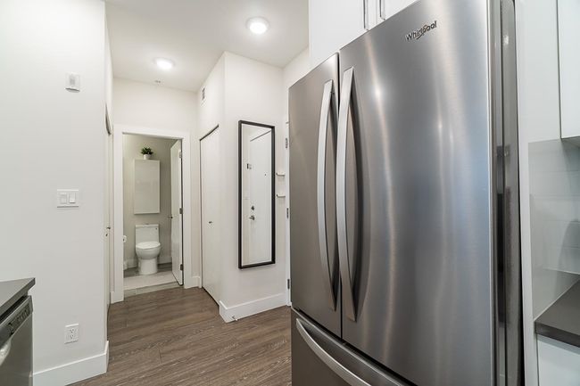 Kitchen featuring dark wood-type flooring, appliances with stainless steel finishes, baseboards, and white cabinets | Image 16