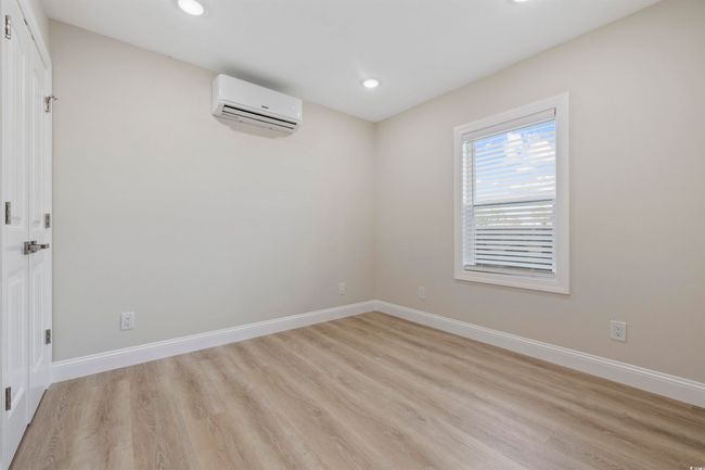 Empty room featuring an AC wall unit, light wood-style floors, recessed lighting, and baseboards | Image 32