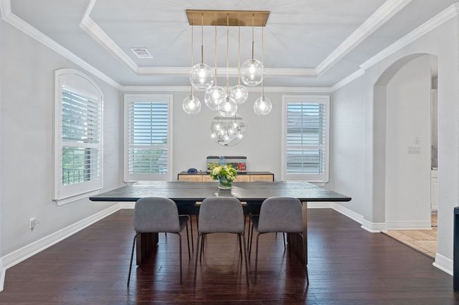 Dining space with a raised ceiling, healthy amount of natural light, arched walkways, wood-type flooring, and crown molding | Image 11
