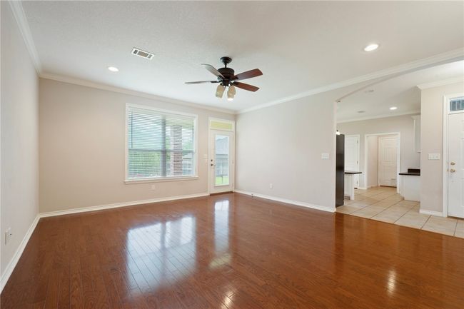 Spare room with ceiling fan, light wood finished floors, baseboards, arched walkways, and crown molding | Image 22