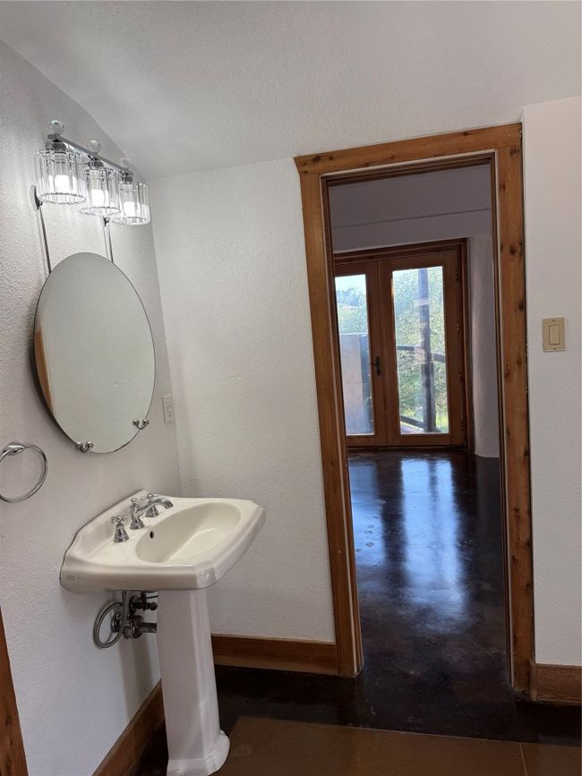 Bathroom with baseboards, finished concrete floors, lofted ceiling, french doors, and a sink | Image 16
