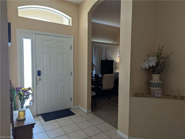 Entrance foyer featuring arched walkways, light tile patterned floors, baseboards, and light carpet | Image 4