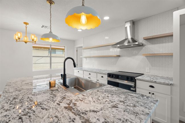 Kitchen featuring wall chimney exhaust hood, open shelves, a sink, and electric range oven | Image 8
