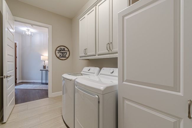 Laundry room featuring independent washer and dryer, cabinet space, baseboards, and light wood-style flooring | Image 25