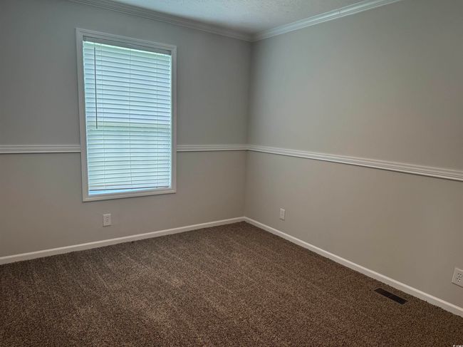 Spare room featuring dark carpet, plenty of natural light, and ornamental molding | Image 25