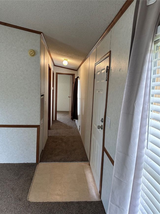 Corridor featuring ornamental molding, a textured ceiling, and light colored carpet | Image 26